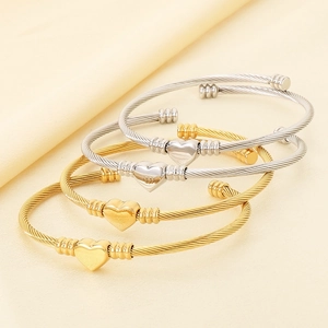 Détail de bracelets torsadés à motif cœur en or et argent avec textures en spirale