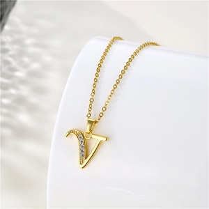Macro detail of gold 18K plated V-letter pendant with sparkling zircon on O-chain necklace