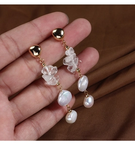 Detail of elegant baroque freshwater pearl drop earrings with gold plating on brown silk