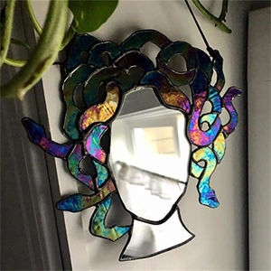 Macro shot of Medusa stained glass suncatcher mirror with rainbow hair on a home wall