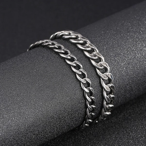Macro shot of silver stainless steel Cuban link chains on a black textured surface