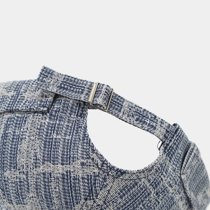 Detail of adjustable silver metal buckle and blue textured woven denim fabric on skullcap