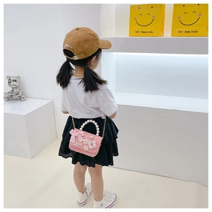 Detailed view of girls pink tweed crossbody bag with pearl handle and bow accent