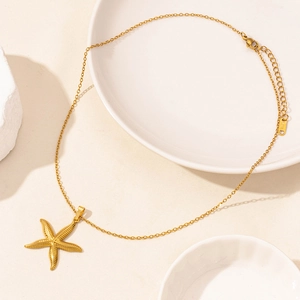 Golden stainless steel starfish pendant necklace on a minimalist stone background