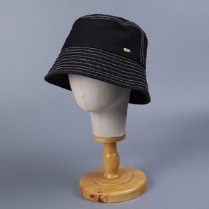 Detail of black canvas bucket hat with decorative multi-row stitching and a gold logo
