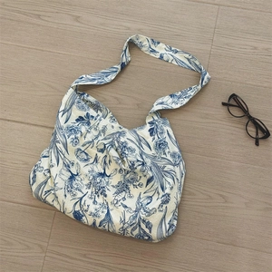 Close-up of blue floral porcelain pattern on off-white canvas tote bag with glasses