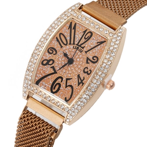Macro shot of rose gold tonneau watch face with rhinestones and Milanese mesh strap