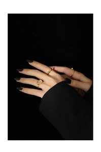 Close-up of golden moonstone rings set on model hands with elegant black aesthetic