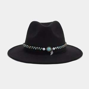 Détail du chapeau fedora noir avec pierre turquoise, perles bleues et pendentif feuille