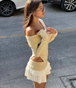 Detail of off-shoulder yellow knit top and white layered pleated mini skirt set