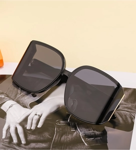 Detail of oversized black square sunglasses with metallic temple accents on a magazine