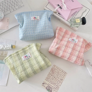 Flat lay of macaron plaid fabric cosmetic bags in blue, pink, and green colors