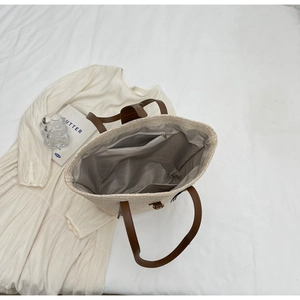Top view of woven tote bag showing beige texture, brown PU straps, and inner pockets