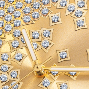 Macro shot of gold watch dial featuring crystal-encrusted octagonal stars and luminous hands