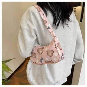 Detailed close-up of pink shoulder bag with cartoon bear pattern and blue bow accent