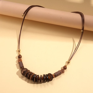 Detail showing the natural texture of dark brown wooden beads and coconut shells on the necklace