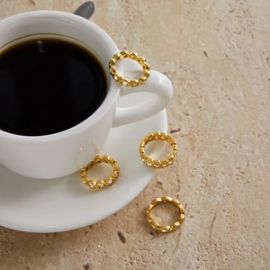 Close-up of four 18K gold stainless steel heart rings with sparkling zircon on a stone surface