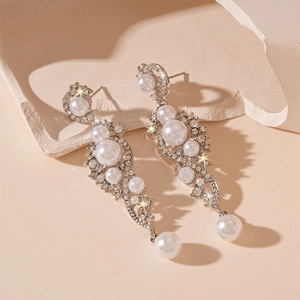 Close-up of elegant silver earrings with sparkling crystals and white pearls on stone