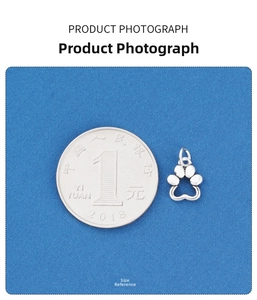 Macro detail of S925 sterling silver hollow cat paw charm next to a coin for size reference