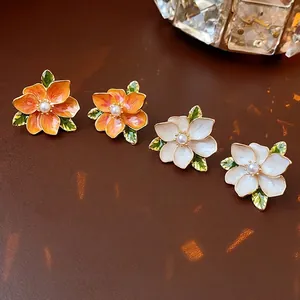 Floral stud earrings with enamel petals and pearl center in orange and white colors