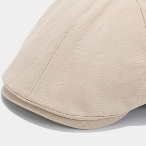 Dettaglio ravvicinato della trama a spina di pesce beige chiaro del cappello newsboy