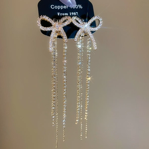 Macro detail of bow tassel earrings with micro-set white rhinestones on copper base