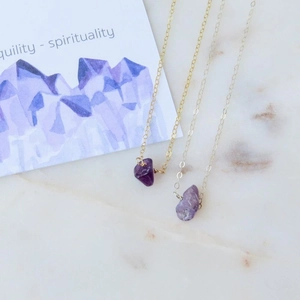 Close-up of gold and silver necklaces with natural irregular purple crystal pendants
