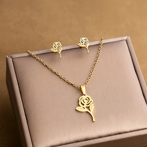 Detailed view of gold hollow rose pendant and matching earrings set in a gift box