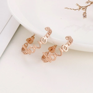 Detail of rose gold stainless steel LOVE earrings on a white ceramic tray