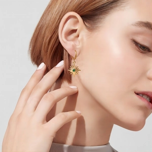 Ohrringe aus 18K vergoldetem Edelstahl mit Sonnenanhängern und grünen Steinen am Model