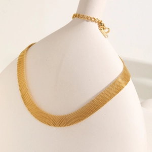 Detail shot of golden mesh chain necklace with lobster clasp around a ceramic vase
