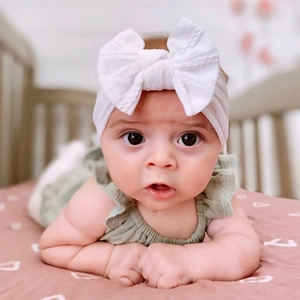 Baby girl wearing a soft white nylon bow headband with stretchy fabric set for infants