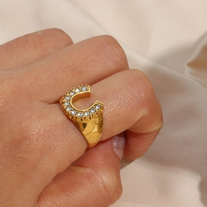 Detailed view of U-shaped gold plated ring with inlaid zircons on a model's hand