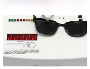 Close-up of black square sunglasses on UV400 tester showing anti-ultraviolet protection