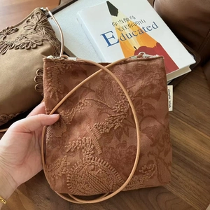 Détail de la broderie florale sur un sac bandoulière vintage en daim couleur camel