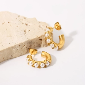 Detail of 18K gold C-shaped earrings with rows of white pearls on natural stone base