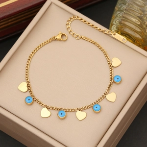 Goldenes Edelstahlarmband mit Evil Eye und Herzanhängern auf einer Schmuckschatulle
