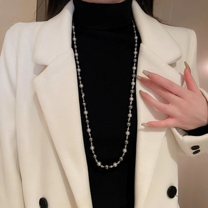 Détail de perles gris argenté et billes de métal sur col roulé noir et blazer blanc chic