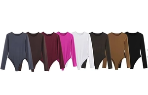 Flat lay of long sleeve bodysuits in eight assorted solid colors on a white background