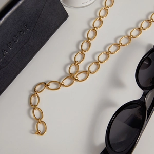Polished 18K gold stainless steel oval link chain necklace displayed with accessories