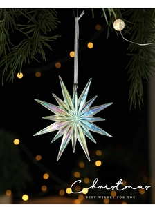Iridescent star ornament hanging on green pine branch with warm golden bokeh lights