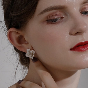 Elegant camellia flower stud earrings with white pearl petals worn by a model