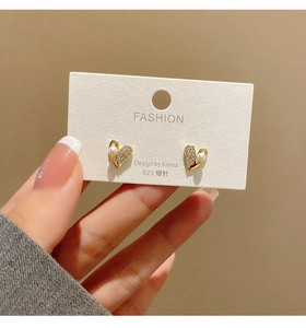 Detailed view of heart stud earrings with pearls and 925 silver needle on display card