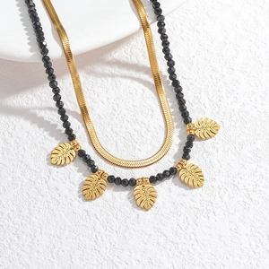 Double-layer layered necklace with golden snake chain, black beads, and monstera leaf pendants