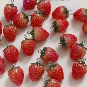 Detailed view of realistic red resin strawberry charms with silver hooks for DIY jewelry