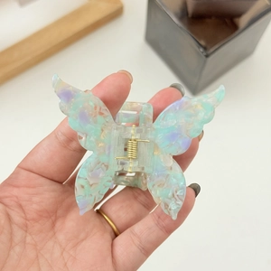 Macro shot of butterfly hair claw clip with colorful iridescent resin and golden spring