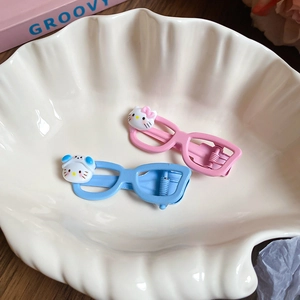 Detailed macro view of cute cat shaped glasses hair clips in pink and blue finish