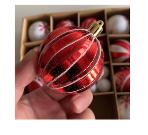 Close-up of red shiny Christmas ball with white glitter stripes and gold hanging loop
