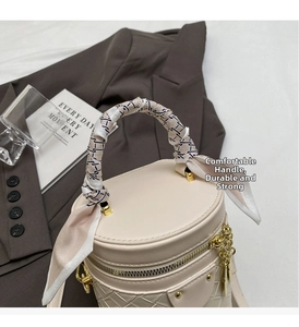 Detail of beige bucket bag with woven texture, metal zipper, and silk scarf on handle