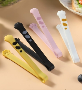Detailed view of four colorful cat paw silicone food tongs on a cozy kitchen table